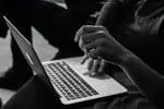 Laptop user typing on keyboard in a dark setting, representing digital music marketing.