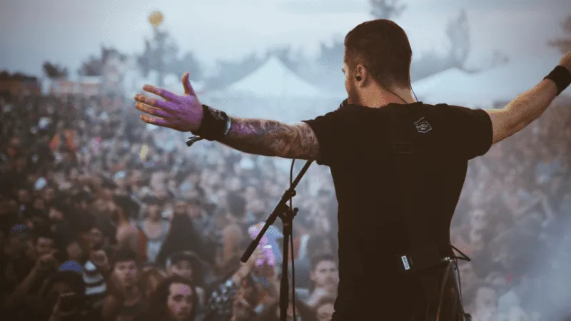 Live music performance at a concert festival with an artist engaging the crowd, showcasing musical event atmosphere and audie