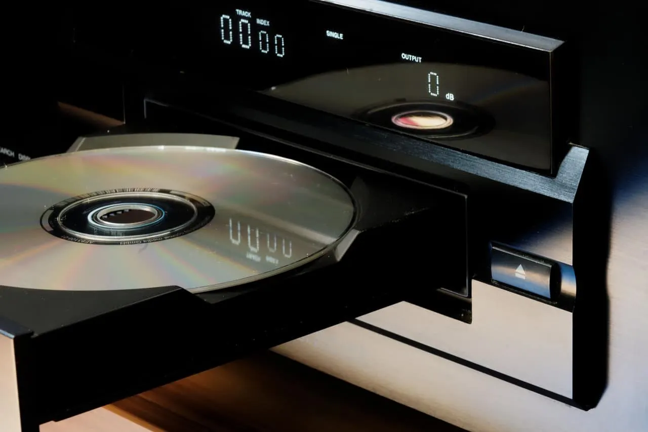 CD player with disc inserted, digital display showing track and output levels, modern music equipment for professional audio