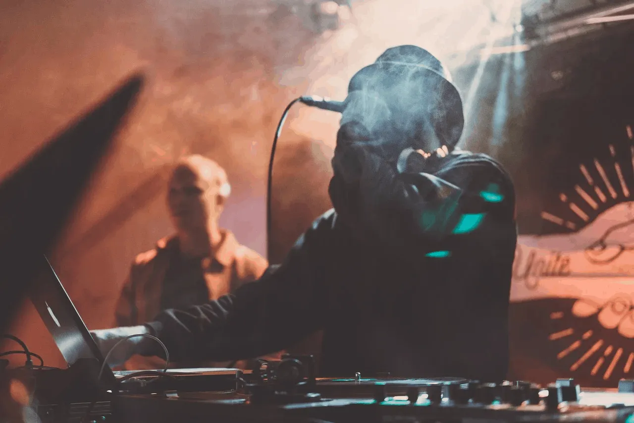 Dynamic DJ performing live with turntables and mixing console at a vibrant music event, illuminated by colorful stage lights