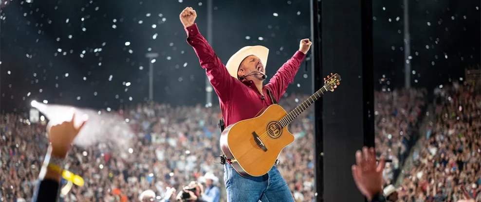 Celebrating a live music performance at a concert with a guitarist passionately playing on stage, surrounded by a large enthu