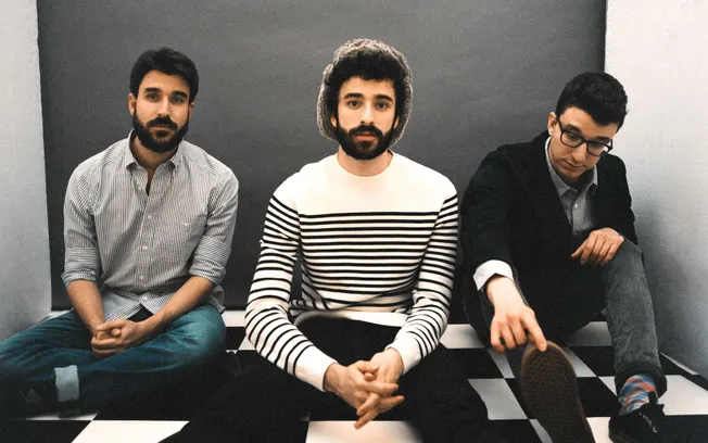 Young men sitting on a black and white checkered floor in a modern studio, casual fashion, indie music band style, creative t