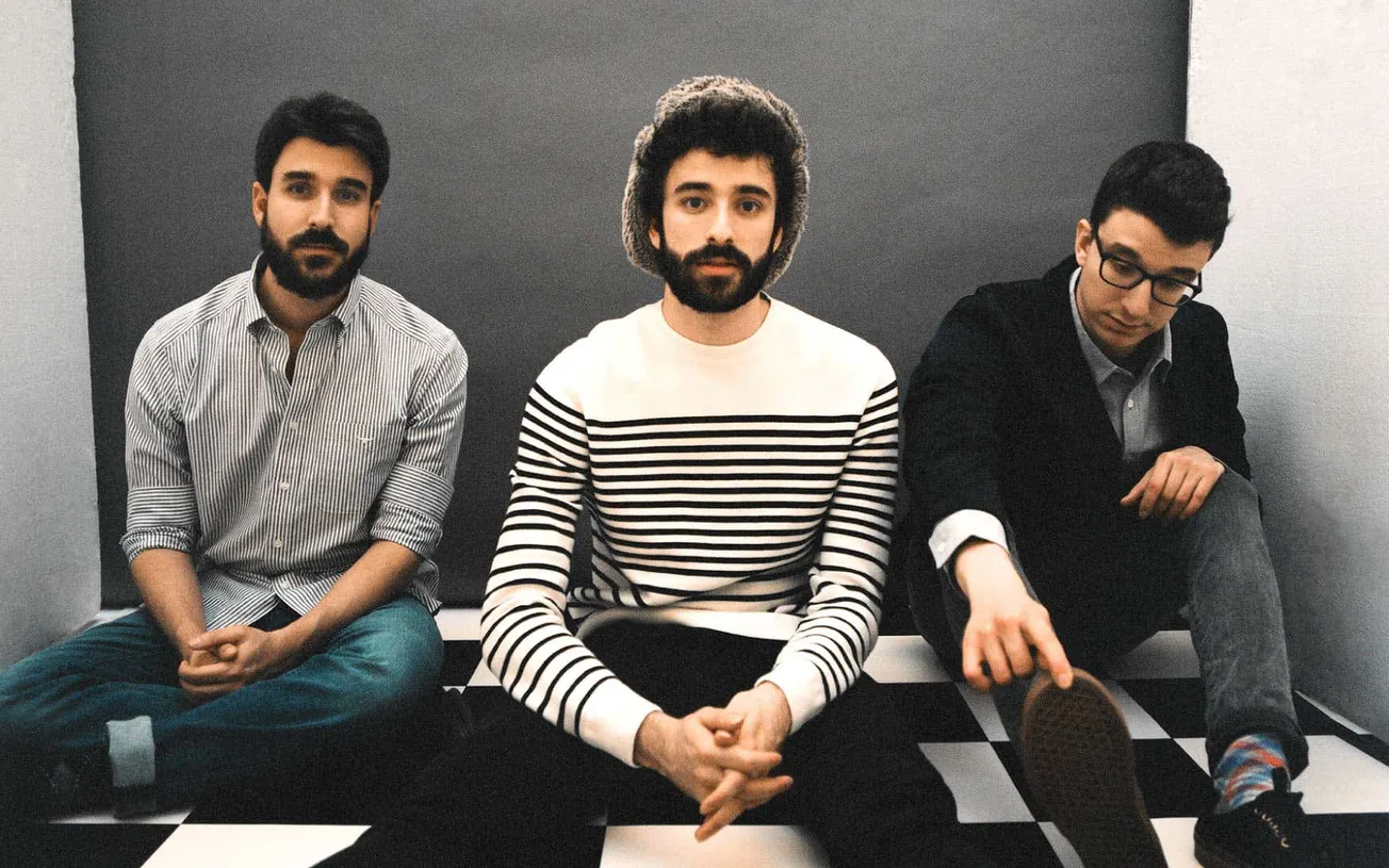 Young men sitting on a black and white checkered floor in a modern studio, casual fashion, indie music band style, creative t
