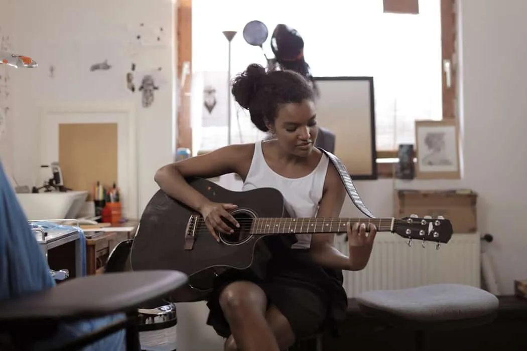Girl playing acoustic guitar in cozy home music studio, young woman practicing guitar, casual musician, creative workspace, m